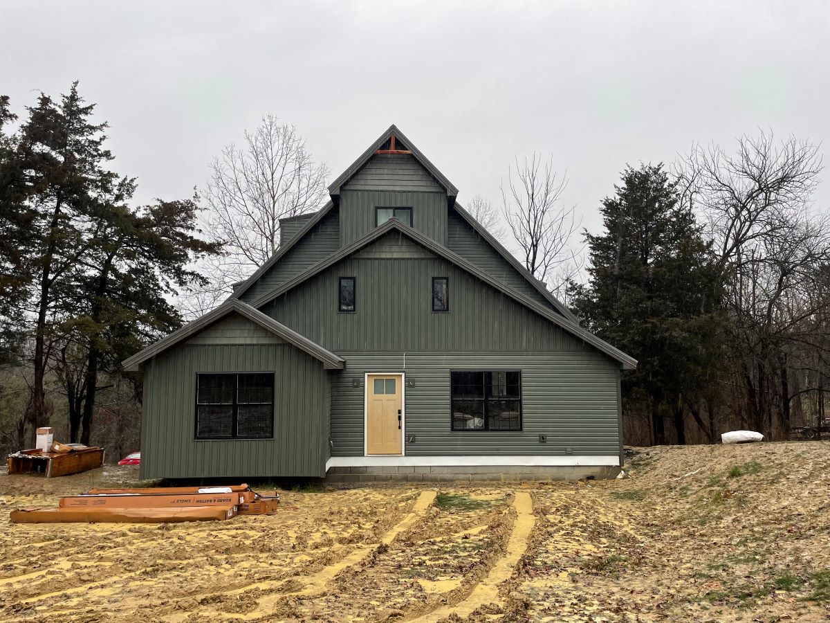 Green house under construction with muddy yard.