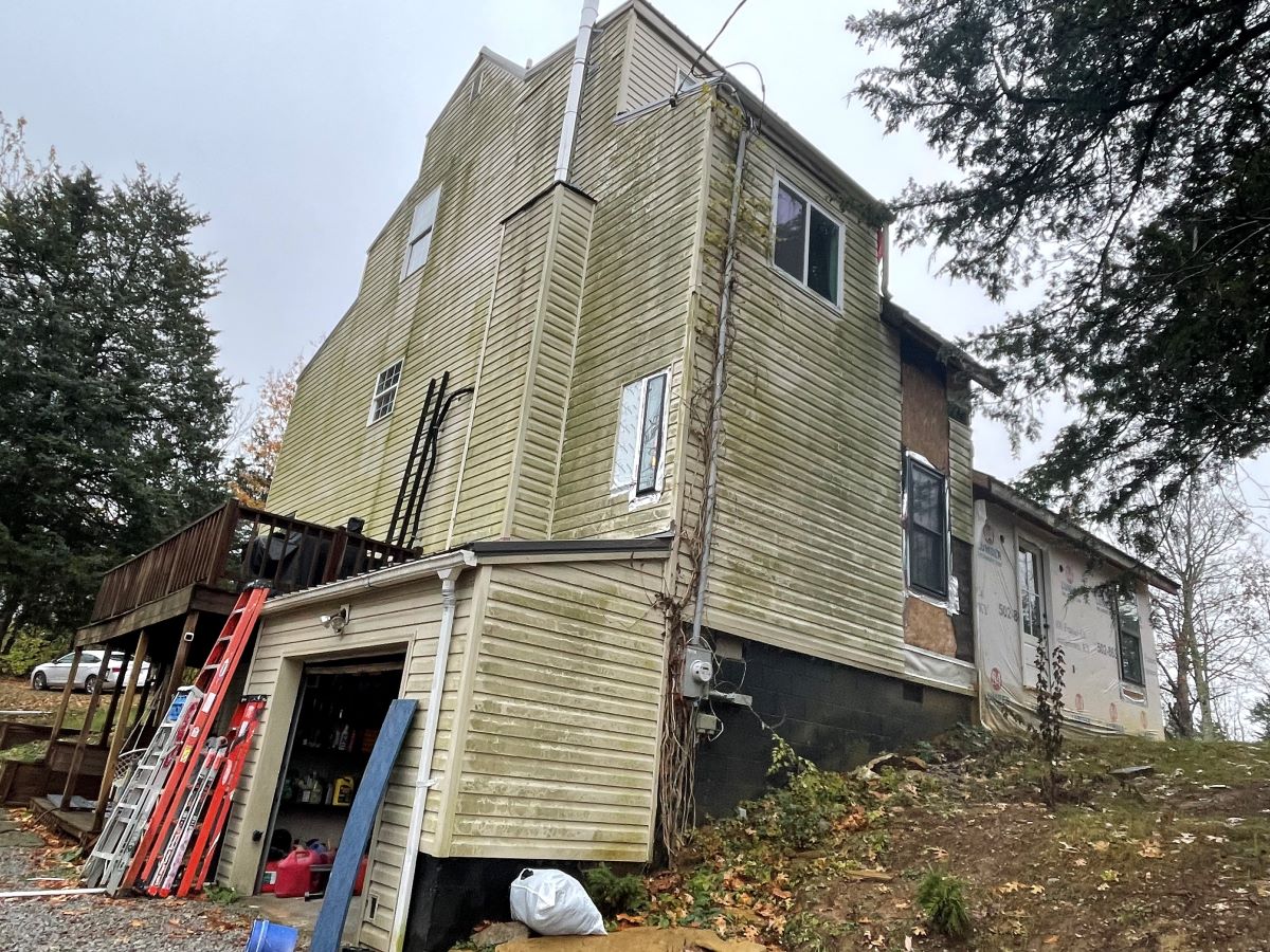 Weathered house under renovation with ladders outside.