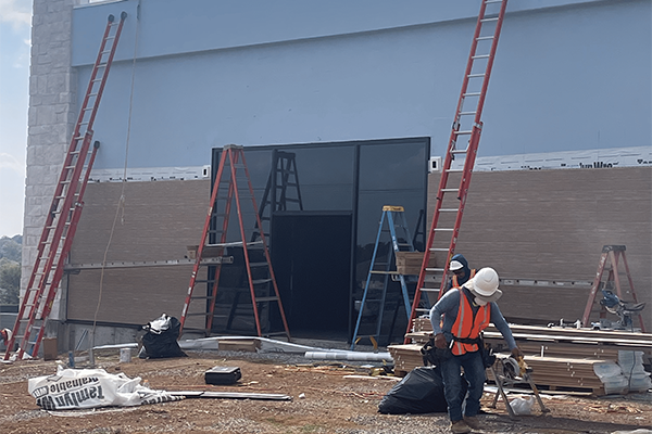 Construction workers and ladders at building site.